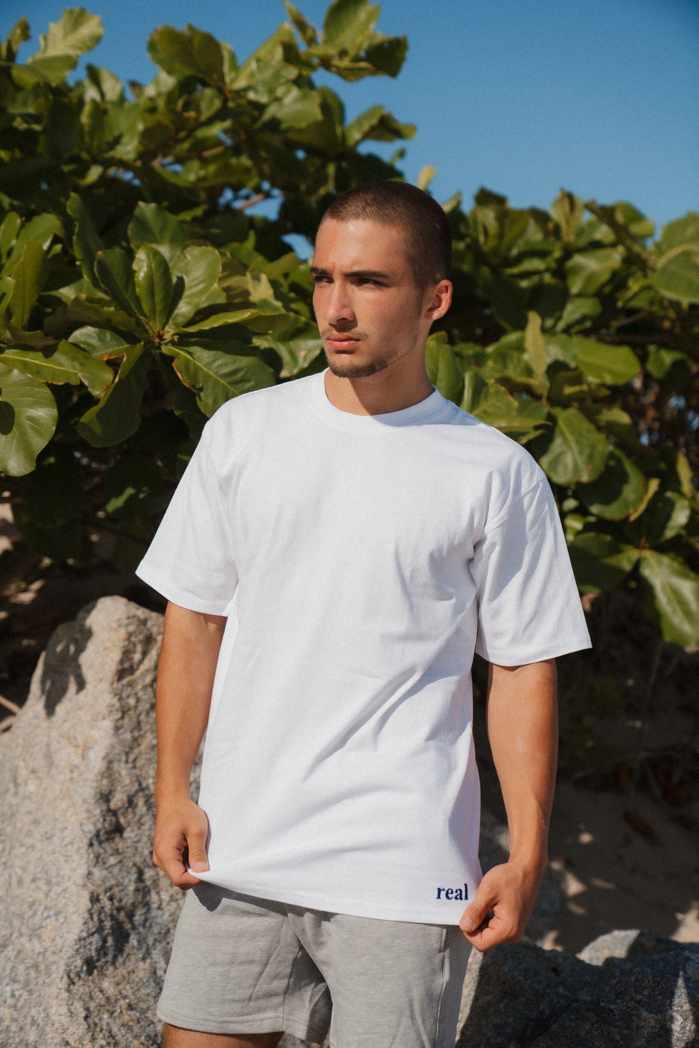 Men's White Tee with dark purple "real" embroidered on the left hip area | RaileyReal