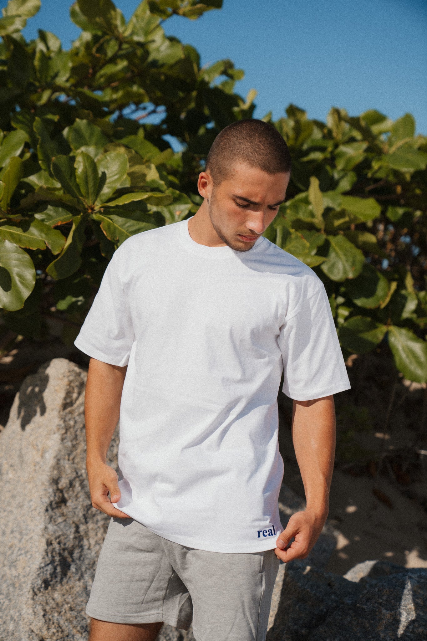 Women's White Tee with dark purple "real" embroidered on the left hip area | RaileyReal